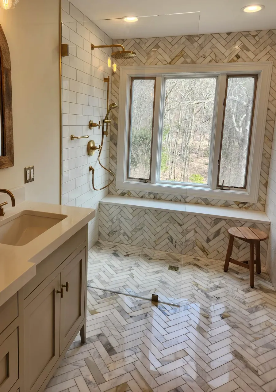 Bathroom remodel in Canton, CT with herringbone marble floors and walls, a curbless shower and brushed brass fixtures