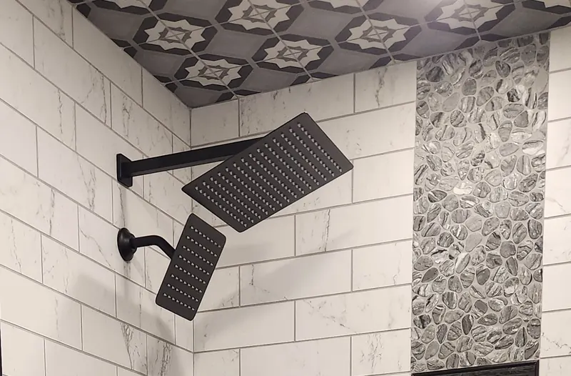 Bathroom remodel in Southington, CT with a patterned tile ceiling, river rock accent through the niches and matte black fixtures